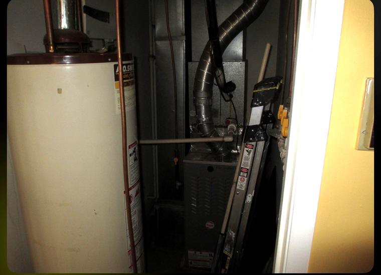 Old water heater and furnace in a cramped utility closet before replacement