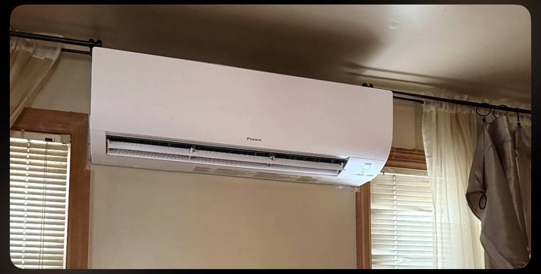 Wall-mounted Daikin ductless indoor head installed above a window