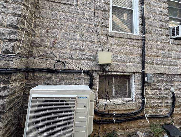 Daikin ductless outdoor condensing unit with line sets run in covered channels up a block wall