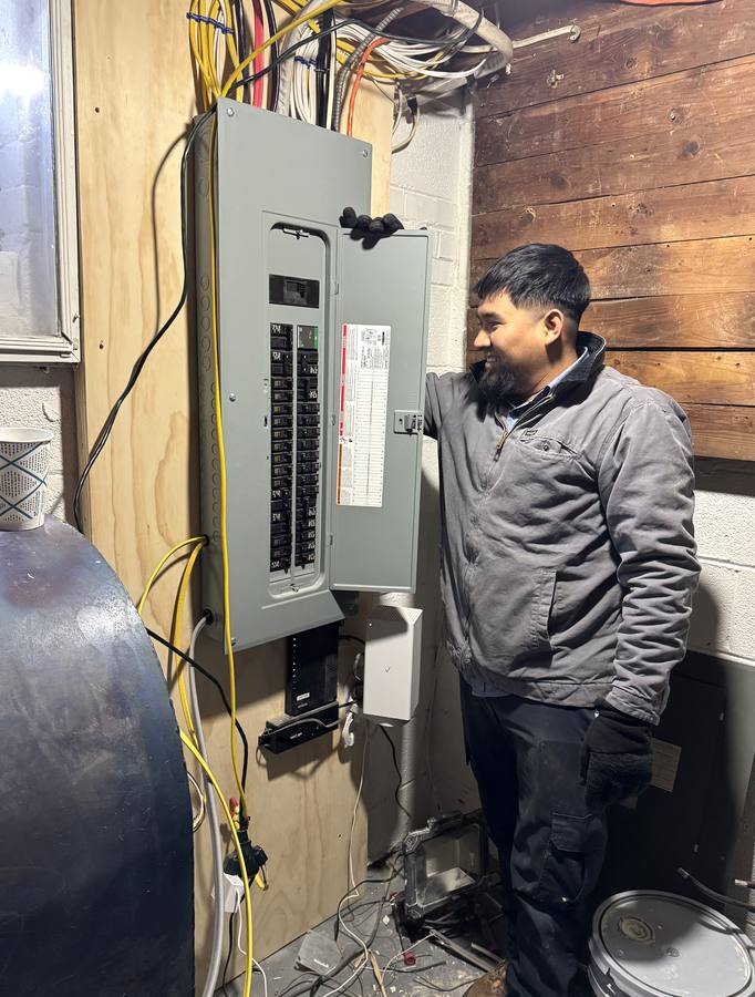 Direct Water Heaters technician beside a newly installed electrical panel with the circuit directory filled in