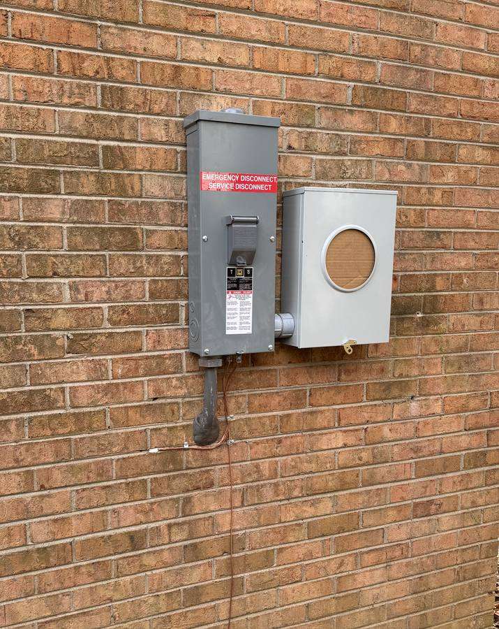 New exterior electrical meter socket and service disconnect mounted on a brick wall