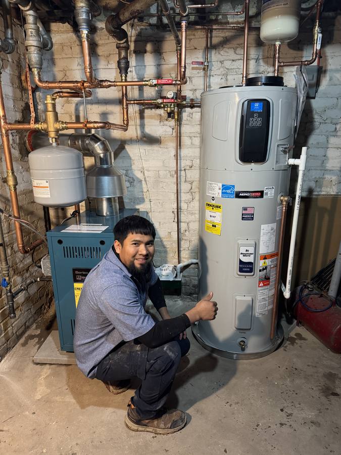 Direct Water Heaters technician beside a newly installed Bradford White AeroTherm heat pump water heater and U.S. Boiler Series 2 boiler